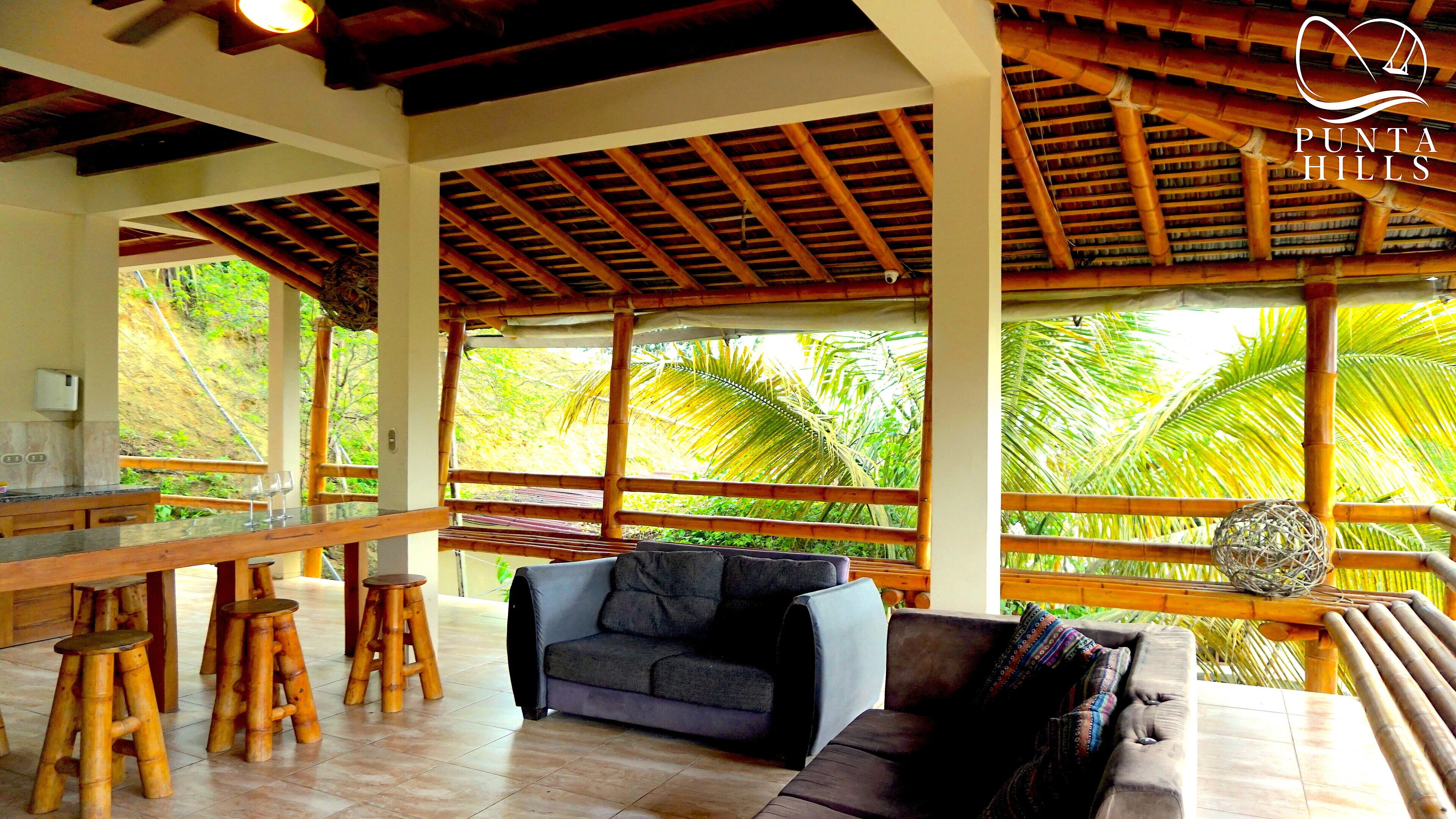 Amplia habitación con techo de madera, un sofá, una mesa y vistas a exuberante vegetación.