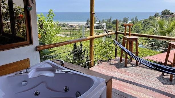 Ein Balkon mit Meerblick, einer Whirlwanne und einer Hängematte.