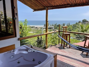 Een balkon met uitzicht op de oceaan, een jacuzzi en een hangmat.