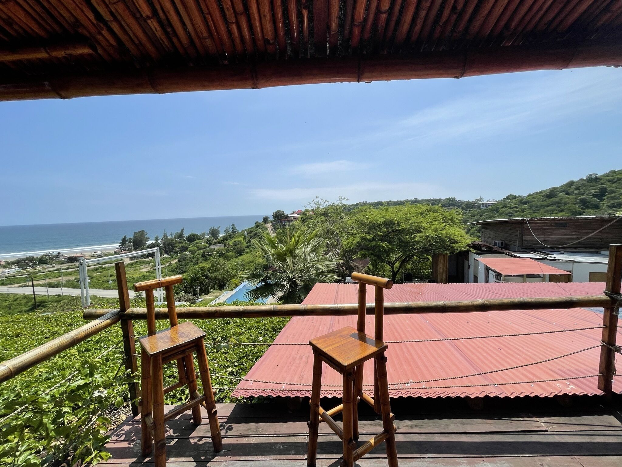 A balcony with a view of the ocean and greenery.