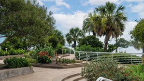 Un jardín ajardinado con palmeras, un sendero curvo y una barandilla.