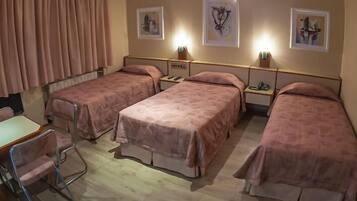 A hotel room with four beds, a desk, and a chair.