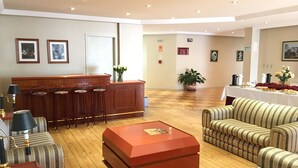 A spacious lobby with a reception desk, bar stools, a coffee station, and striped sofas. - Cosmos Hotel (Caxias do Sul)