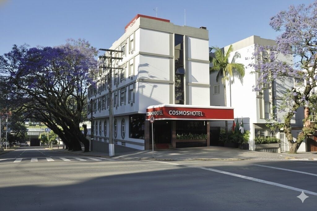 A building with a Cosmoshotel sign, a large tree, and a clear sky.