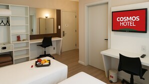 A hotel room with a bed, a desk, a chair, a TV, and a wardrobe. - Cosmos Hotel (Caxias do Sul)