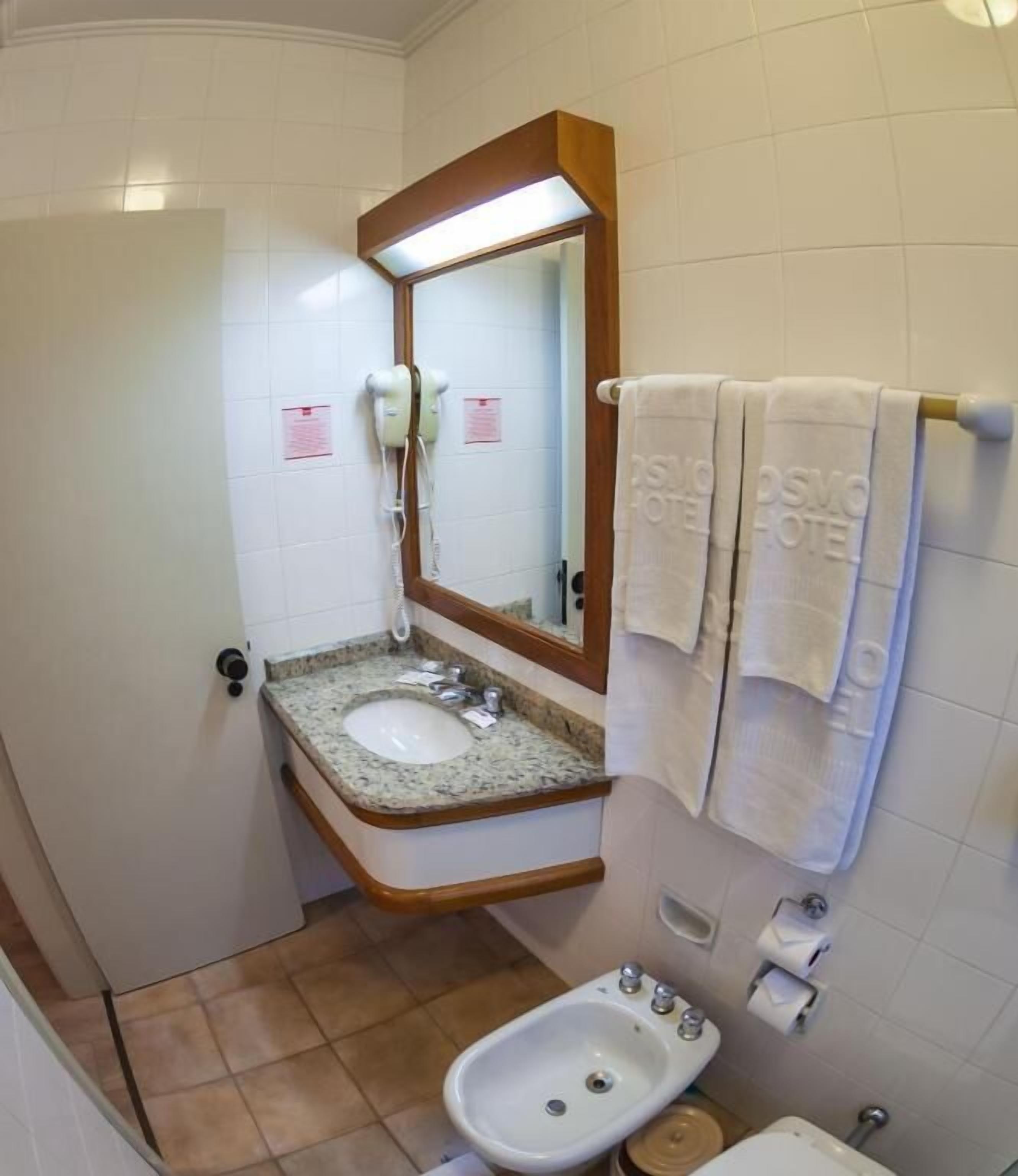 Une salle de bain avec un lavabo doté d’un plan de travail en granit, un miroir, un bidet et un porte-serviettes avec des serviettes.