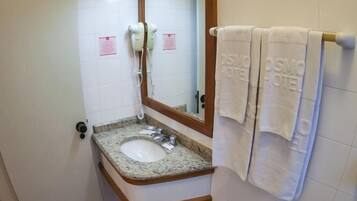 Une salle de bain avec un lavabo doté d’un plan de travail en granit, un miroir, un bidet et un porte-serviettes avec des serviettes.