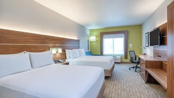 A hotel room with two beds, a desk, a chair, a TV, and a window.