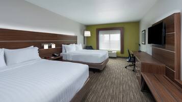 A hotel room with two beds, a TV, a desk, and a window.