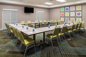 A conference room with long tables, yellow chairs, water bottles, and framed artwork on the walls. - Holiday Inn Express Troy by IHG (Troy)