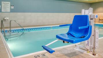 An indoor pool with a blue chair lift, clear pool rules sign, and a tiled floor.