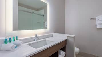 A modern bathroom with a large mirror, a sink, and a toilet.