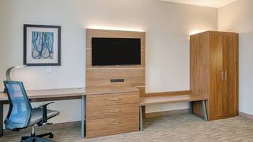 A modern office space with a desk, chair, TV, and wardrobe.
