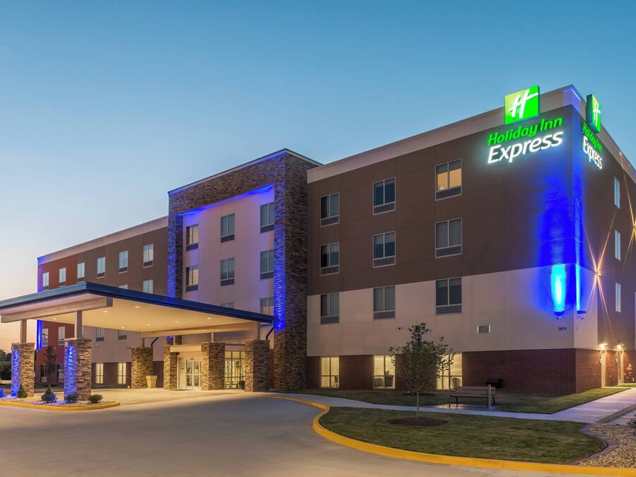 Un hotel Holiday Inn Express con diseño moderno, que cuenta con una entrada destacada y una zona de estacionamiento techada.