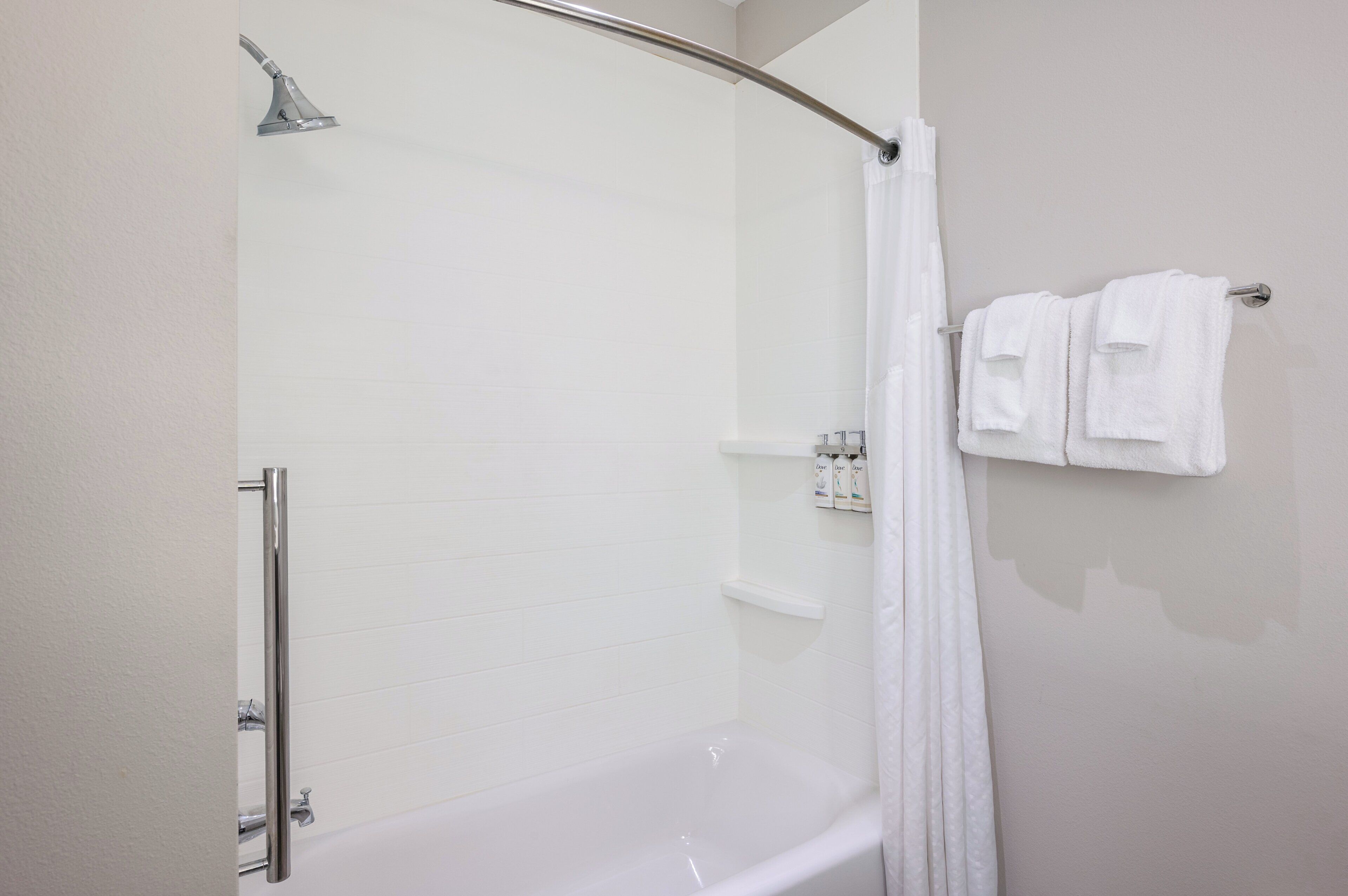 Ein modernes Badezimmer mit einer in Glas eingefassten Dusche, einer weißen Badewanne und einem Handtuchhalter mit gefalteten Handtüchern.