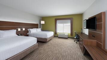 A hotel room with two beds, a desk, a TV, and a window with blinds.