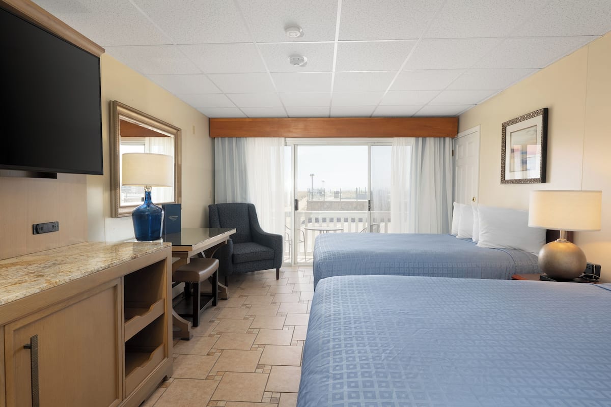 A hotel room with a bed, a desk, a chair, a TV, and a balcony with a view.