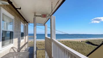 Enjoy the serene beach view from this covered porch with a table and chairs.