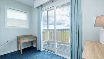 A room with a bench, a table, a window with blinds, and a view of the outdoors through a sliding door.