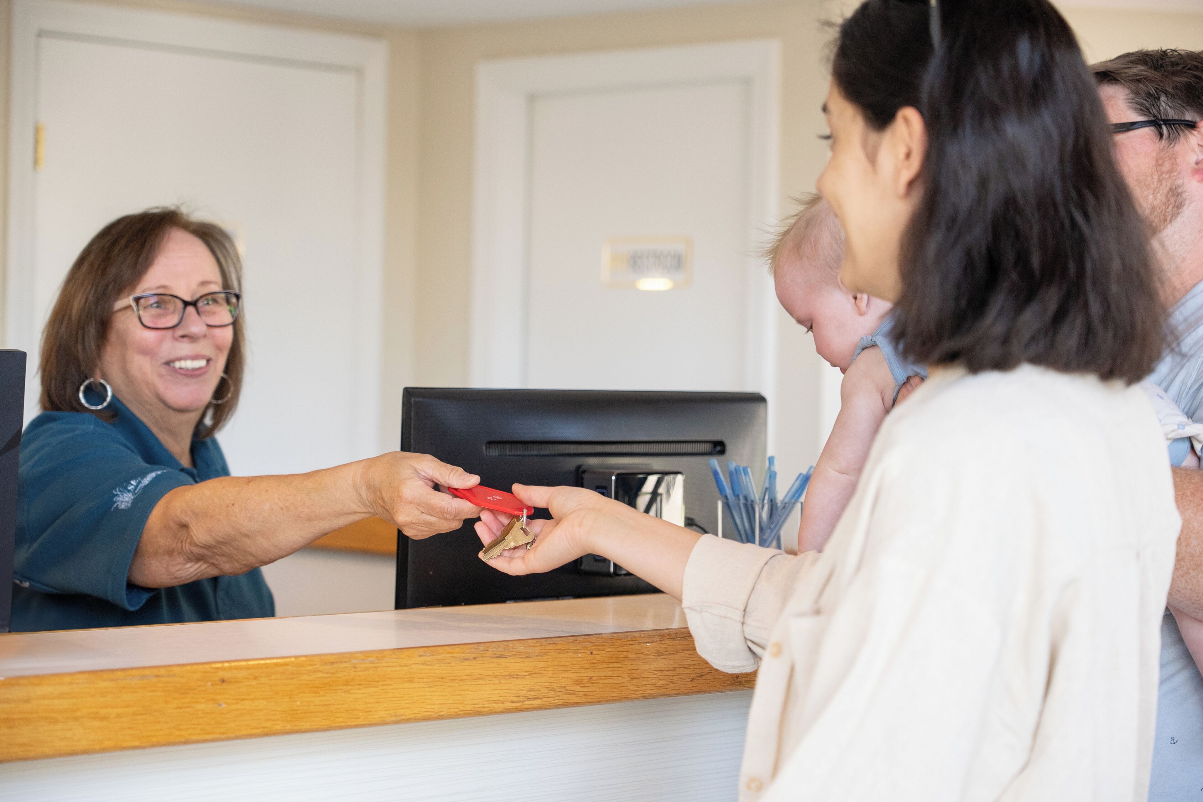 Una recepcionista entrega una llave a un huésped en la recepción.
