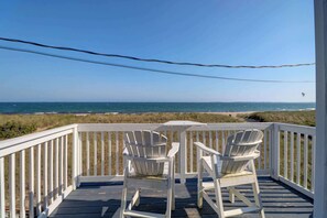 A wooden deck with two white Adirondack chairs facing a beach. - Waves Oceanfront Resort (Old Orchard Beach)