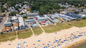 Vista aérea de una playa con numerosos paraguas y gente.