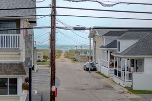 A coastal street with houses, a car, and a view of the ocean. - Waves Oceanfront Resort (Old Orchard Beach)