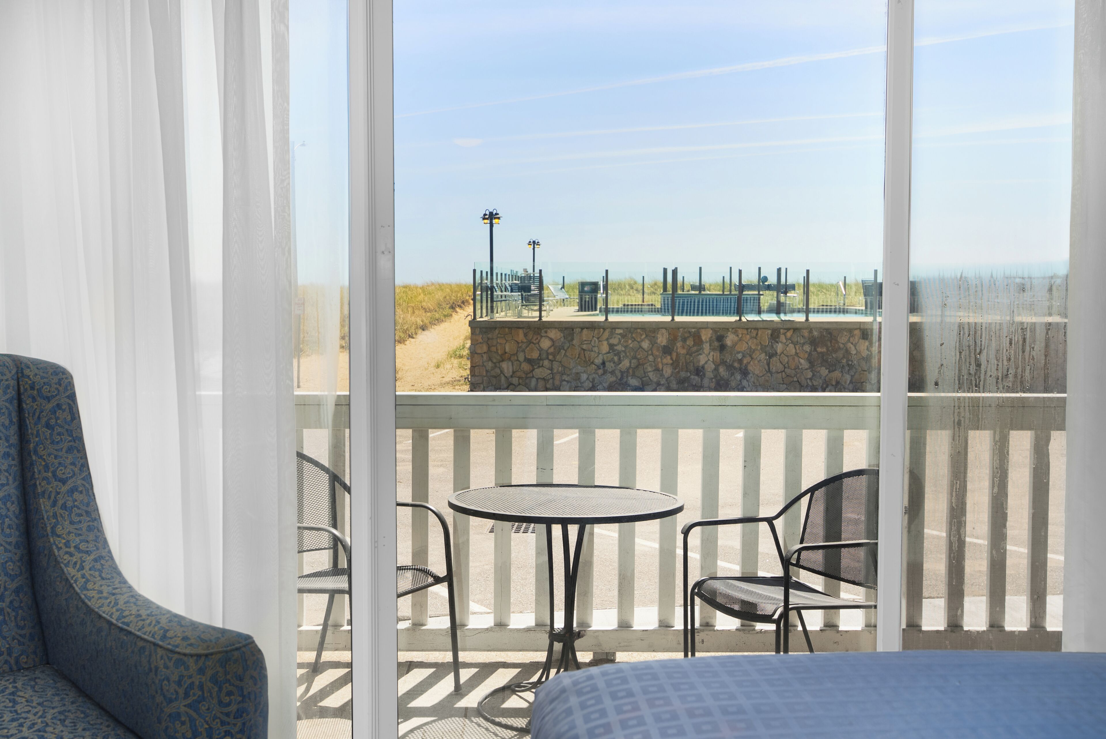 En balkon med udsigt over stranden, et bord og to stole.