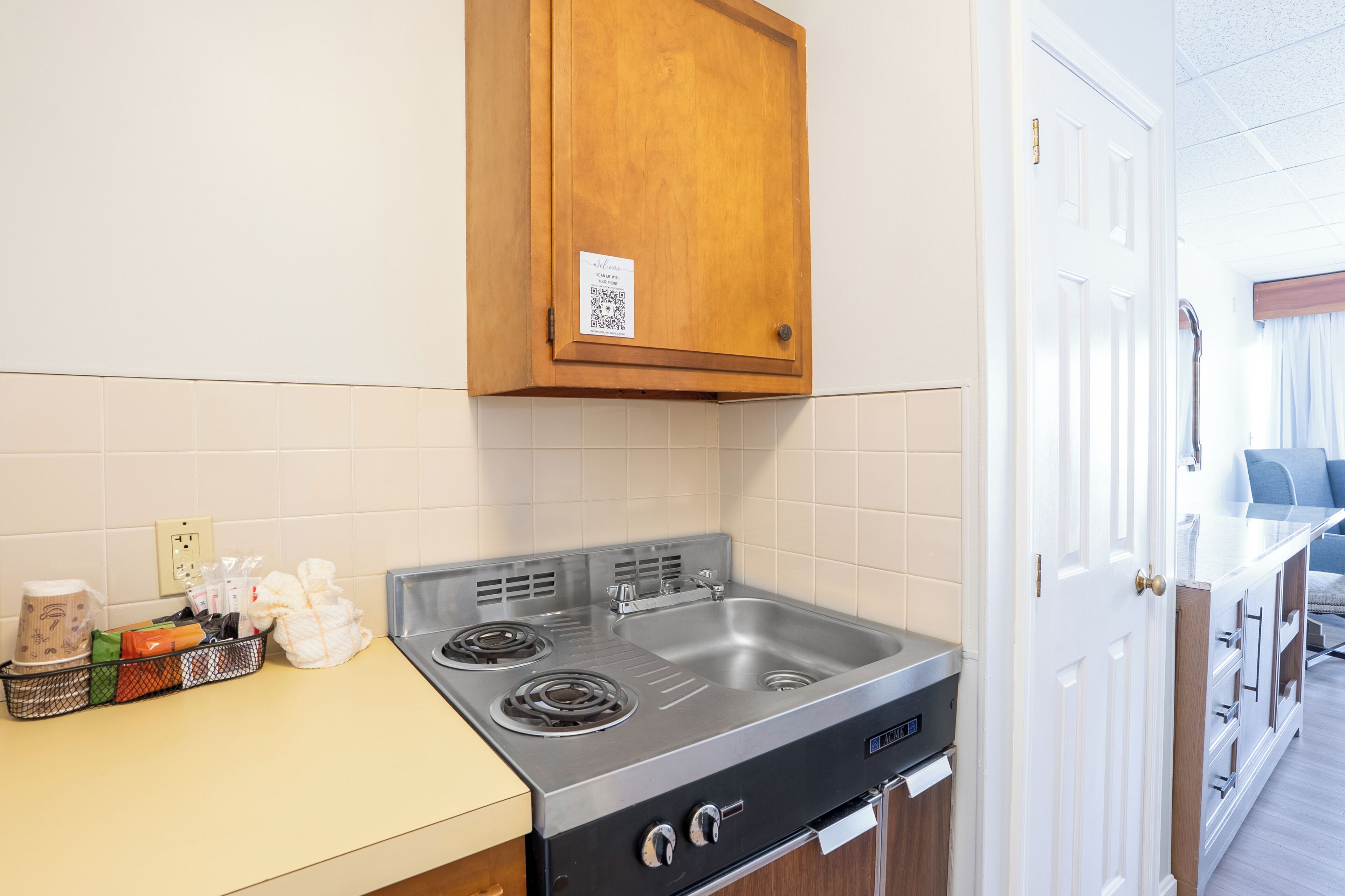 A kitchen with a stainless steel stove, a wooden cabinet above it, and a white door to the right.