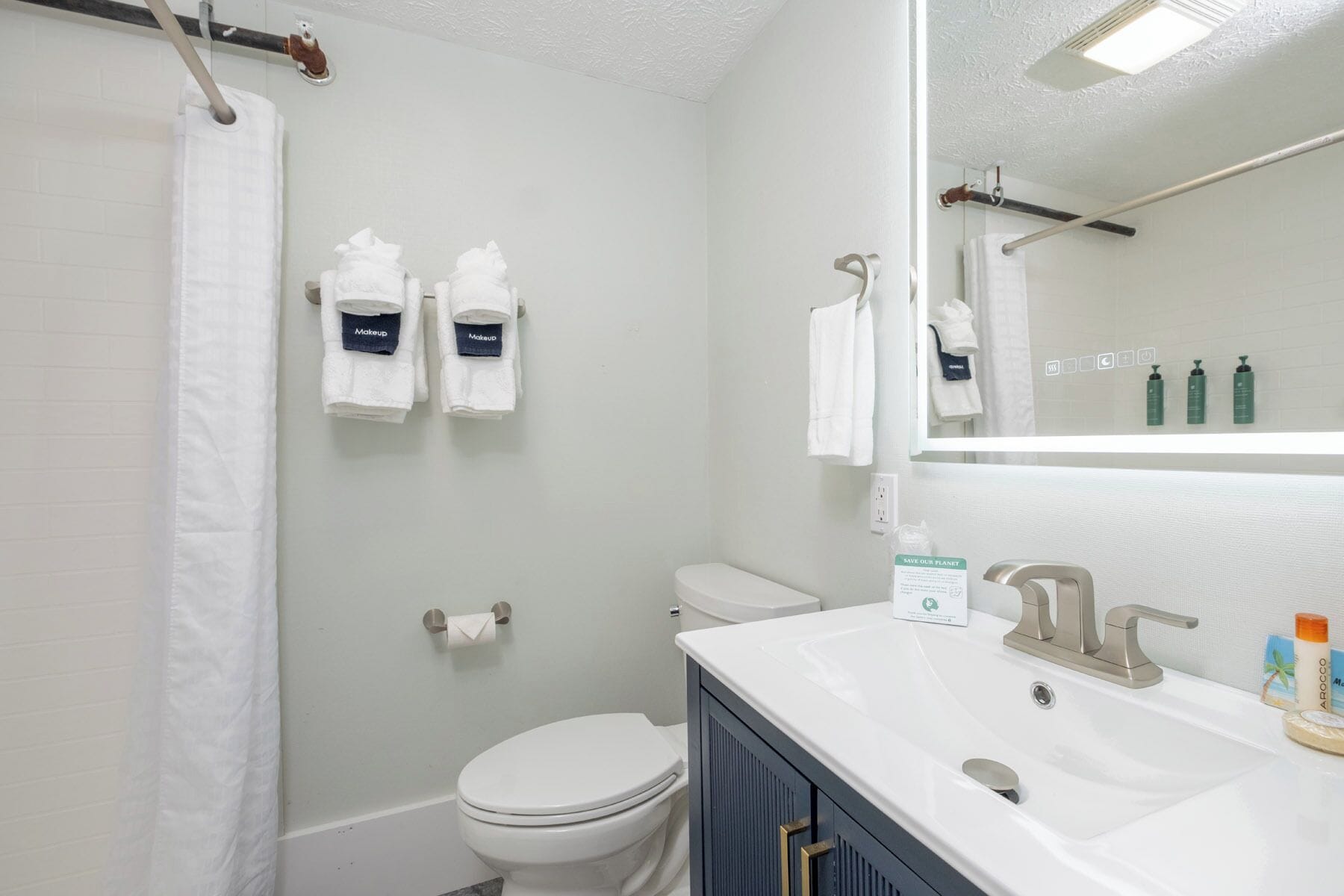 A bathroom with a white toilet, a sink with a mirror, and two towels hanging on hooks.