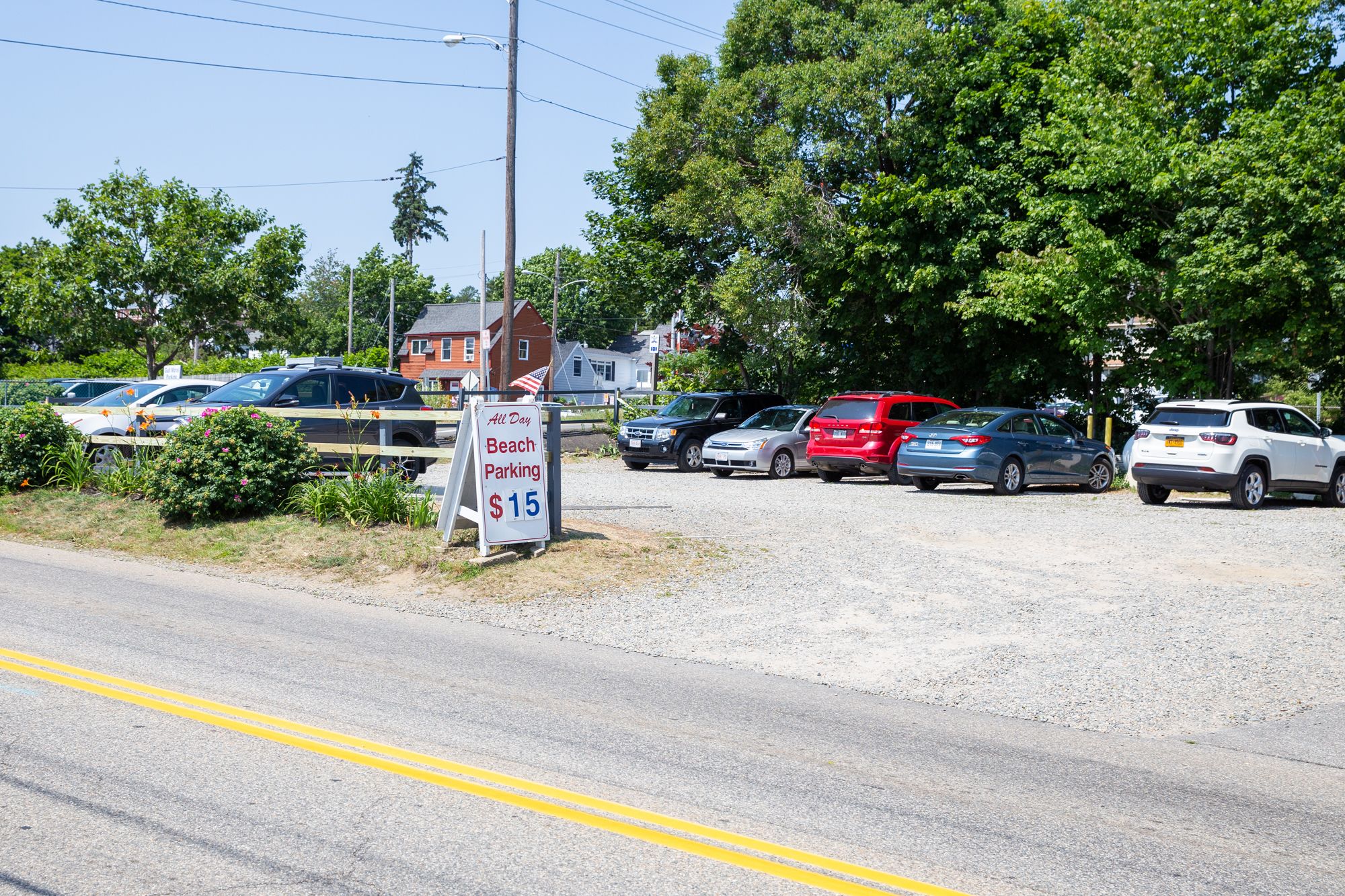 A parking lot with a sign indicating all-day beach parking at $15.