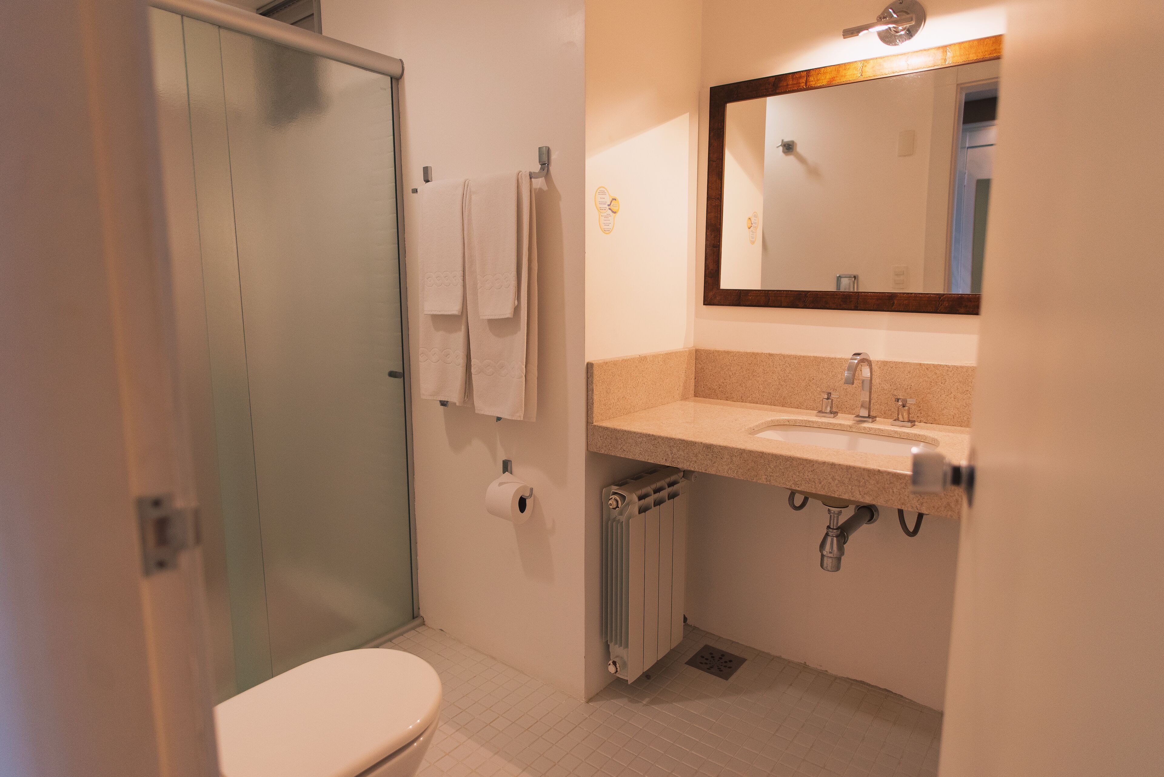 A bathroom with a toilet, a sink, a mirror, and a towel rack.