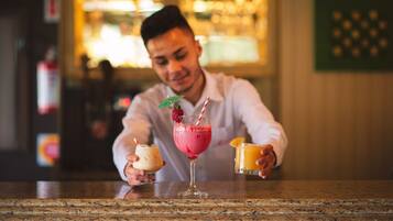 A bar setting with a person holding two drinks, one in a tall glass and another in a short glass.