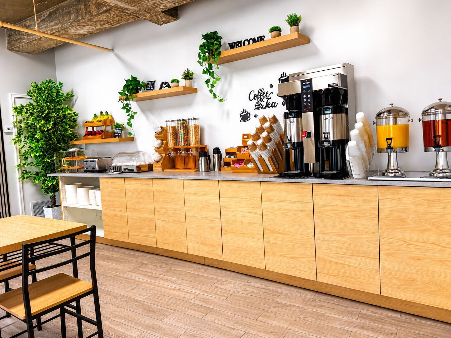 A coffee bar with a wooden counter, coffee machines, dispensers, and a sign that says 'Coffee & Tea'.