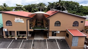 A hotel named Hotel Del Rio with a red roof, a reception desk, and a parking area. - Hotel del Rio (Liberia)