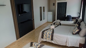 A hotel room with a bed, a TV, a refrigerator, and a door. - Hotel del Rio (Liberia)