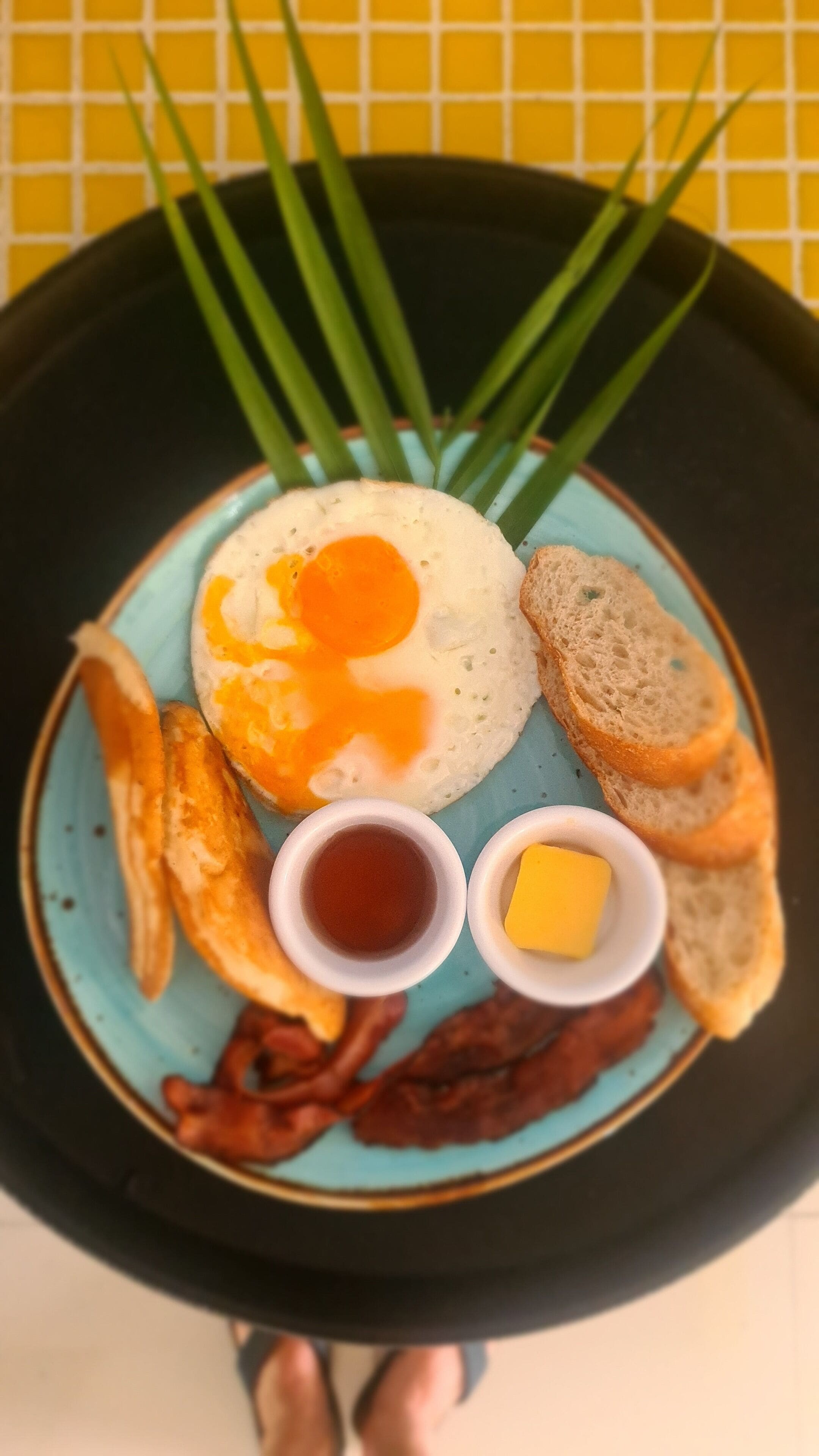 Un piatto per la colazione con uova, pane tostato, pancetta e salse.