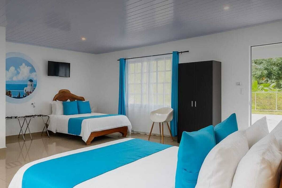 A modern hotel room with a large bed, a desk, and a wardrobe.