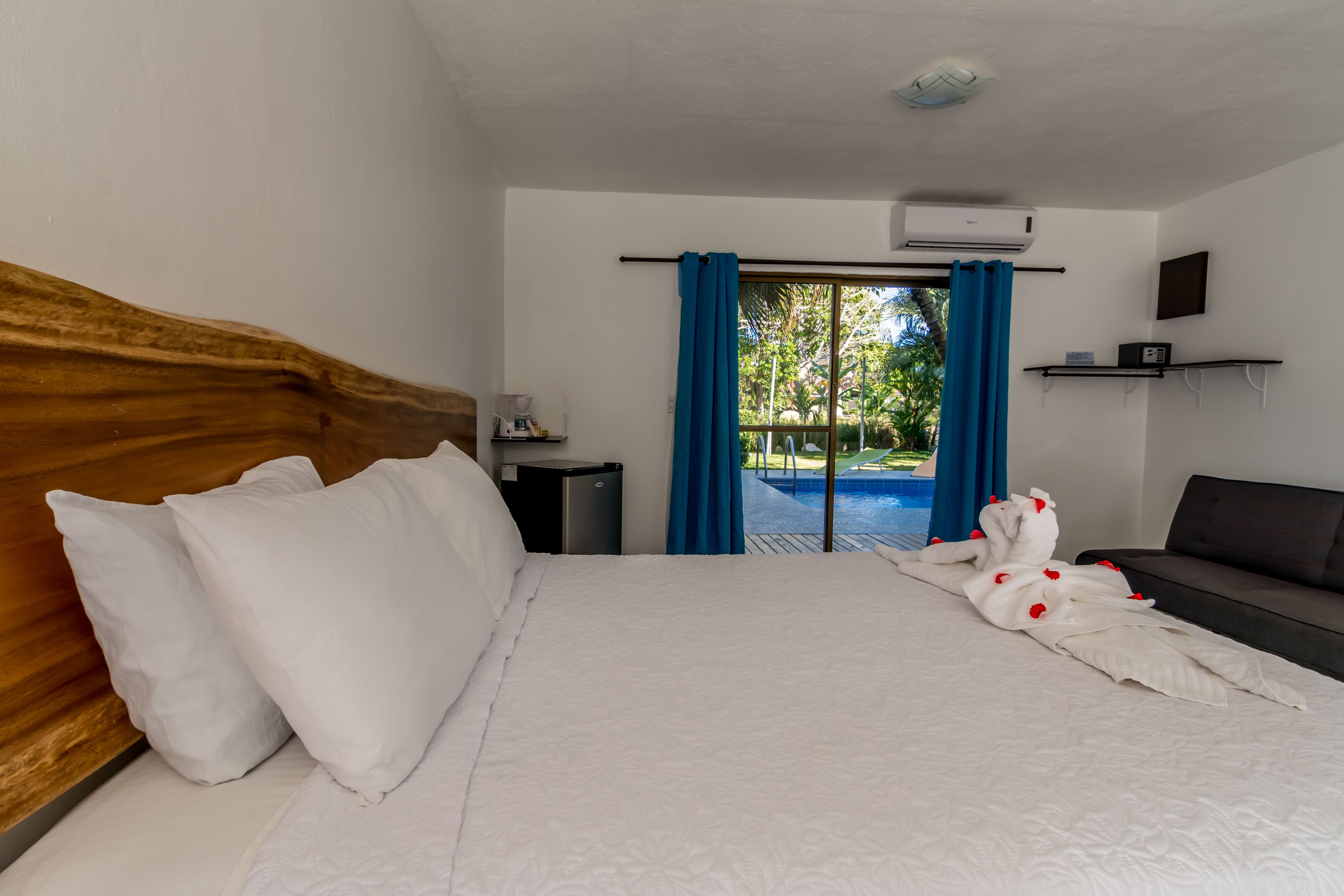 Habitación de hotel con cama, escritorio, televisión y vista a una piscina al aire libre.