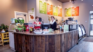 A counter with a wooden finish, a coffee machine, and a menu board in a cafe setting.