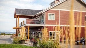 A two-story building with a red exterior, a balcony, and a visible entrance.