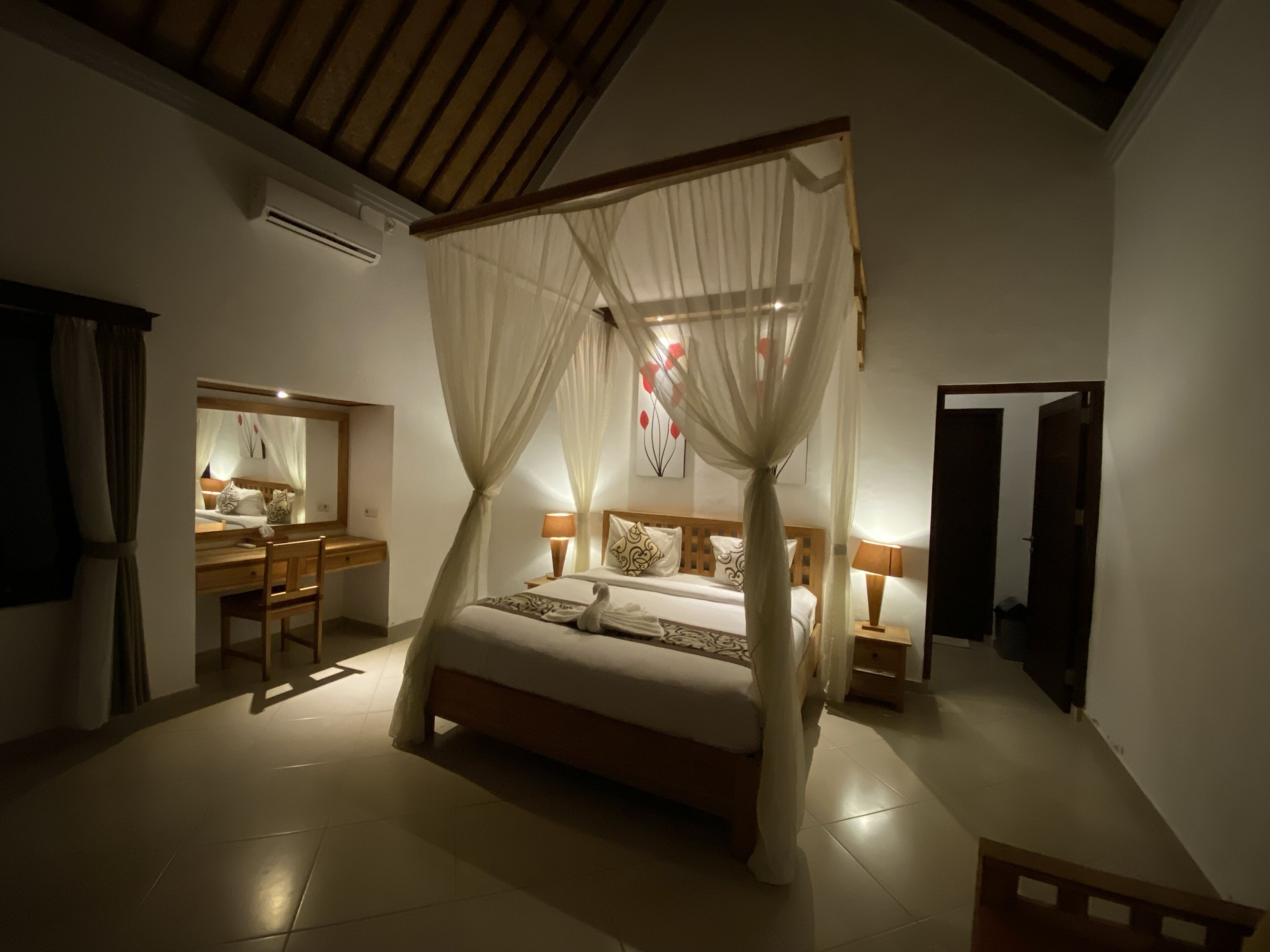 A bedroom with a four-poster bed, a desk, and a chair.