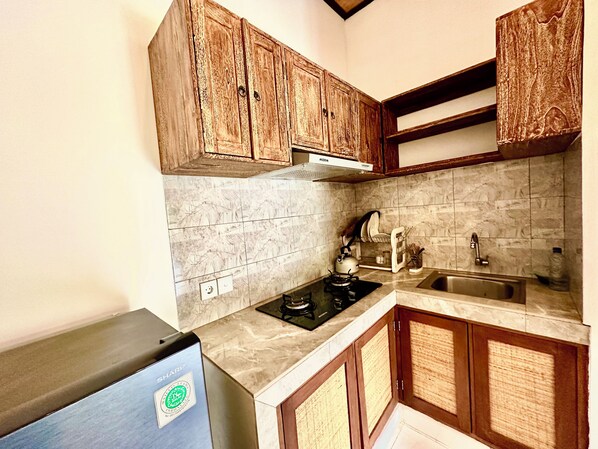 A kitchen with wooden cabinets, a gas stove, a sink, and a marble backsplash. - Dupa Ubud Villa (Ubud)