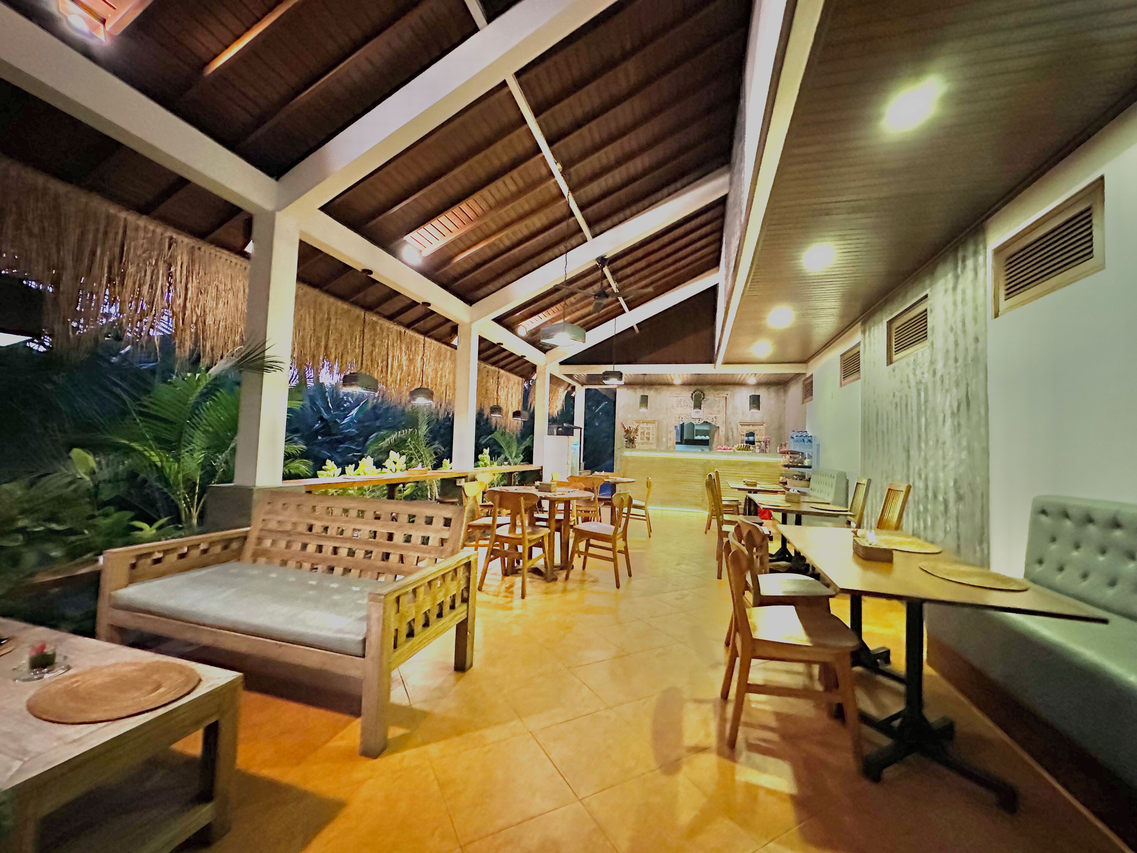 A spacious indoor area with a high ceiling, wooden furniture, and a tropical-themed mural on the wall.
