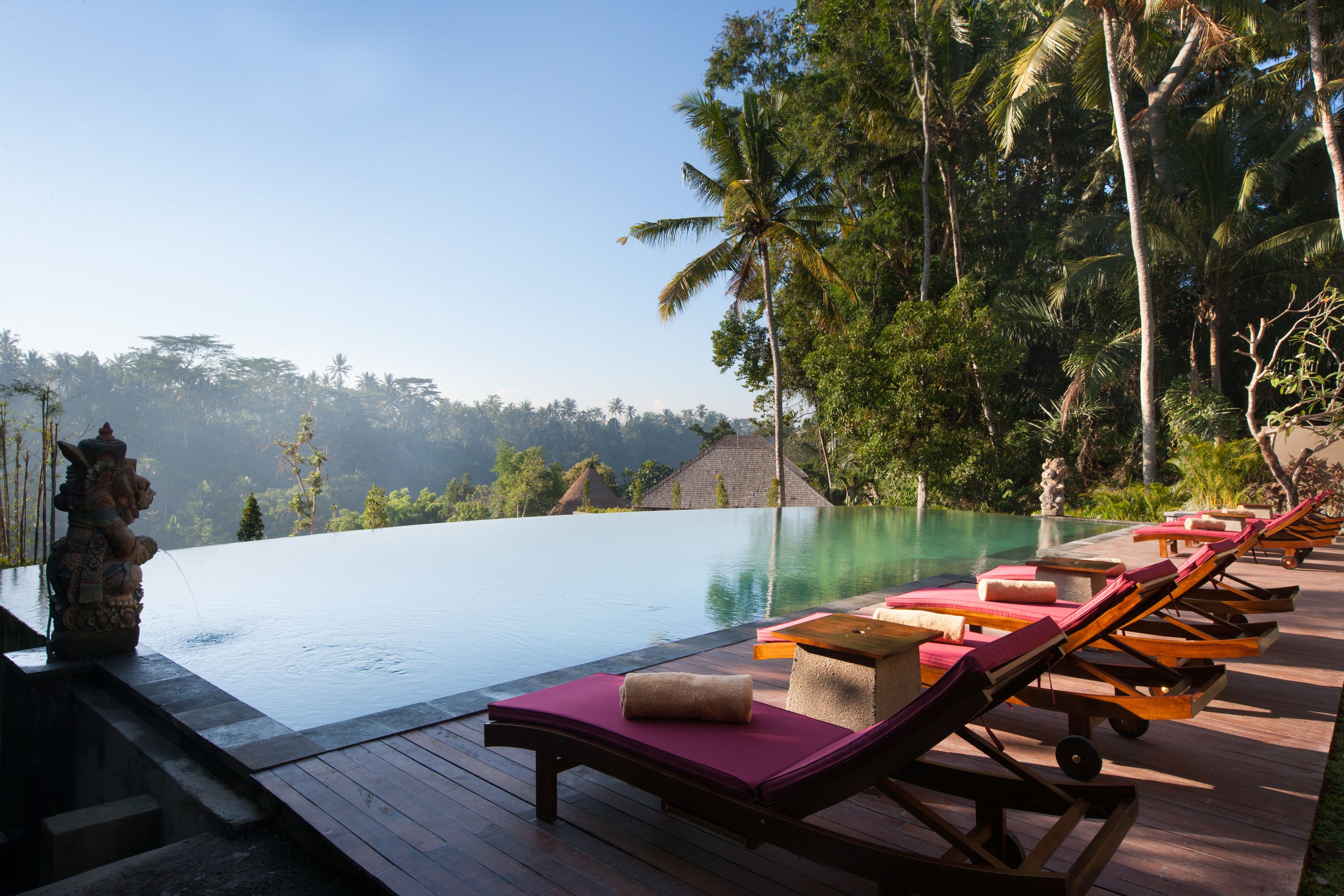 A poolside area with lounge chairs and a statue.