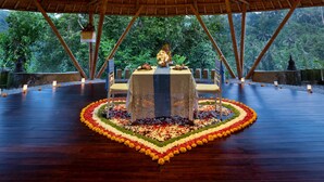Un espacio cubierto con una mesa y sillas centrales, rodeado por un arreglo floral.