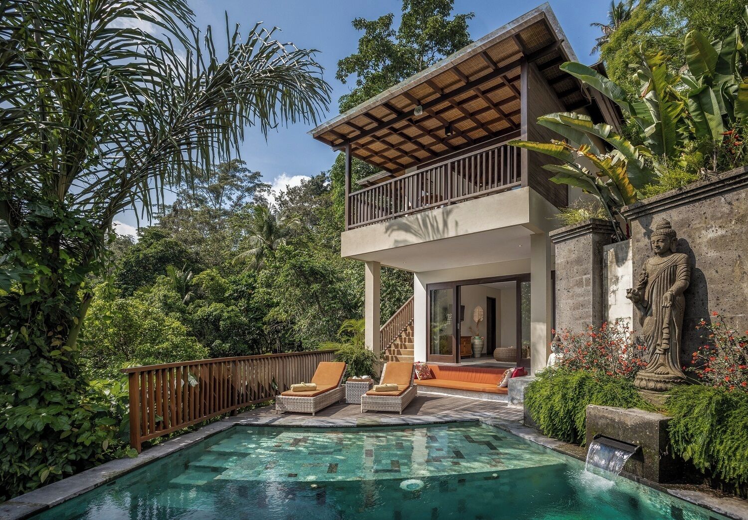 A modern villa with a pool, outdoor seating, and a statue.