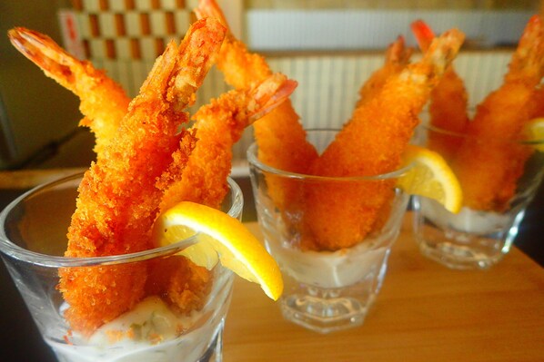 Three glasses of shrimp tempura with lemon slices.