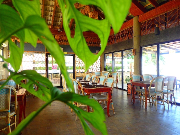 An indoor dining area with wicker furniture and a wooden floor.