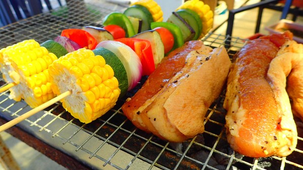 A grill with skewers of corn, vegetables, and chicken. - Aozora Seaside Mactan (Lapu-Lapu)